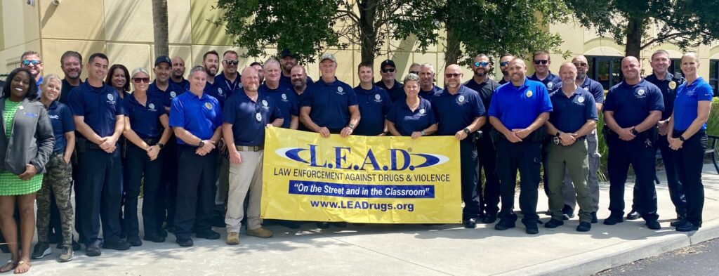 A group of officers pose with a L.E.A.D. banner at the end of their training